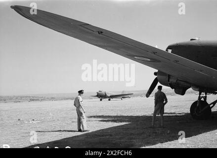 FORCE AÉRIENNE ROYALE : ITALIE, BALKANS ET EUROPE DU SUD-EST, 1942-1945. - Un Douglas Dakota des taxies du No 216 Group RAF jusqu'à son point de dispersion après avoir atterri à Grottaglie, Italie, surveillé par le Pilot Officer F Baggs (à gauche) et le Flight Lieutenant J Brown du No 267 Squadron RAF sous l'aile de leur avion Royal Air Force, Group, 216 (transport aérien et ferry), Royal Air Force, unité de maintenance, 267 Banque D'Images