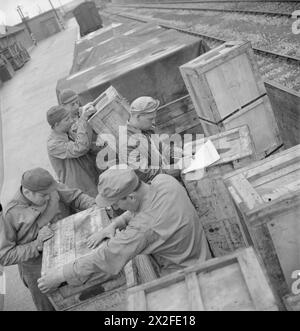 BRITISH GOODS IN US TRIAGE YARDS : ANGLO-AMERICAN Co-OPERATION IN WARTIME BRITAIN, 1943 - les soldats américains déplacent de grandes caisses de pièces de rechange de moteur de voiture à côté de la ligne de chemin de fer dans ce triage américain, quelque part en Grande-Bretagne. Le sergent Charlie Oliver, de Walton Way extension, Augustine, Géorgie (au centre) coche les cases dans l'armée des États-Unis Banque D'Images