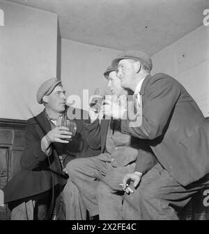 WARTIME PUB : LA VIE QUOTIDIENNE AU WYNNSTAY ARMS, RUABON, DENBIGHSHIRE, PAYS DE GALLES, ROYAUME-UNI, 1944 - trois hommes discutent de divers problèmes locaux autour d'une pinte de bière et d'une cigarette au Wynnstay Arms à Ruabon Banque D'Images