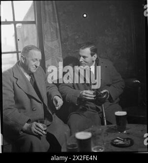 WARTIME PUB : LA VIE QUOTIDIENNE AU WYNNSTAY ARMS, RUABON, DENBIGHSHIRE, PAYS DE GALLES, ROYAUME-UNI, 1944 - le marchand de maïs Harold Davenport (à droite) et le révérend Harold J Crowasdale (à gauche) dégustez une pinte et une conversation dans les bras Wynnstay, Ruabon. Selon la légende originale, le révérend Crowasdale est originaire du Lancashire et a été vicaire de toute l'église Saint à Ruabon pendant sept ans Banque D'Images