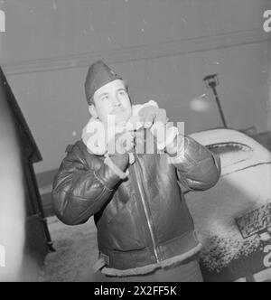 ICI : AMÉRICAINS EN GRANDE-BRETAGNE, 1942 - 23 ans Lieutenant Ronald E Miller est de Mount Morris, Illinois. Ici, il ferme sa veste volante en cuir contre la neige à sa base, quelque part dans le nord de l'Angleterre United States Army Air Forces Banque D'Images