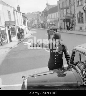 GOUVERNEMENT LOCAL DANS Une VILLE DE CAMPAGNE : LA VIE QUOTIDIENNE À WOTTON-UNDER-EDGE, GLOUCESTERSHIRE, ANGLETERRE, Royaume-Uni, 1944 - le sergent de police S G Auger dirige la circulation dans la High Street à Wotton-under-Edge. En arrière-plan peut être vu l'horloge Tolsey, à l'angle de High Street et Market Street. La légende originale indique que la force de police régulière de Wotton se compose d'un sergent et de deux gendarmes (il y a aussi 22 spécialistes de la guerre). La police relève d'un Comité mixte permanent du comté composé de demi conseillers du comté, demi magistrats. Il y a six divisions dans le comté ; le sergent de Wotton Banque D'Images