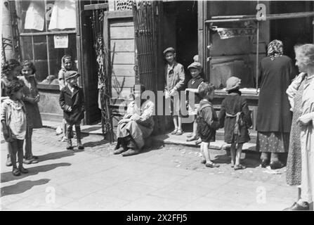 Un groupe de Juifs se réunit devant un magasin de légumes appartenant à Jochwet Abzac, avec une cafétéria voisine servant du thé et du café, dans le ghetto de Varsovie entre octobre 1940 et mai 1943. Banque D'Images