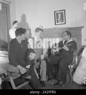 THE SEVEN SEAS CLUB : LIFE AT THE MERCHANT NAVY CLUB, ÉDIMBOURG, ÉCOSSE, 1943 - les hommes séjournant au Seven Seas Club d'Édimbourg apprécient une chanson chantée dans l'une des chambres. Ici, nous voyons Teaka Makario Bou, un combattant français de Tahiti qui joue de la guitare pour Vernon Zocchi de Californie et Igitar Nalard de Norvège Banque D'Images