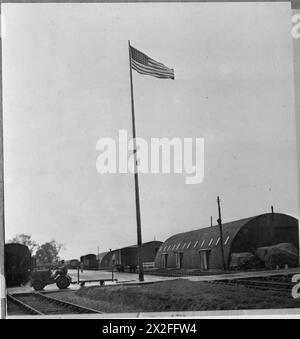 LA GRANDE-BRETAGNE APPROVISIONNE LE MAGASIN DE L'ARMÉE américaine : AMERICANS IN BRITAIN, 1943 - le drapeau américain flotte au-dessus des huttes Romney au toit rond de ce camp construit par les Britanniques, qui sert maintenant de magasin d'alimentation pour l'armée américaine. Au premier plan, le soldat Robert l Starling du 347 Liberty Street, Jacksville, Floride, conduit le camion. Dans la vie civile, le soldat Starling conduisait des camions pour la Economy Cab Company de Jacksville Banque D'Images