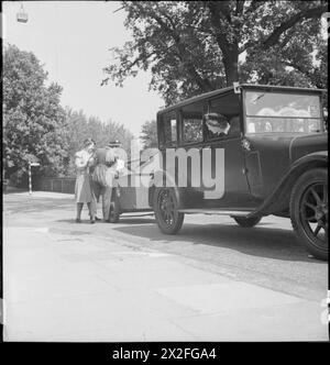 NOURRITURE POUR PORCS : LE SERVICE VOLONTAIRE DES FEMMES COLLECTE LES DÉCHETS DE CUISINE RÉCUPÉRÉS, EAST BARNET, HERTFORDSHIRE, ANGLETERRE, 1943 - Mme Gerald de Rivaz, chauffeur de WVS, regarde de l'intérieur de la voiture de collecte de nourriture pour porcs, tandis que Kathleen Kent (à gauche) et Winifred Jordan vident le contenu d'une poubelle à porcs dans la remorque. Ces déchets de cuisine récupérés seront utilisés comme nourriture pour porcs Banque D'Images