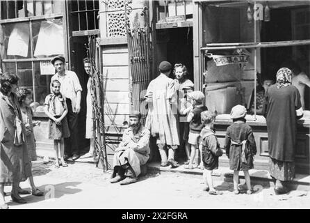 Un groupe de Juifs se réunit devant le magasin de légumes de Jochwet Abzac sur la rue Miła dans le ghetto de Varsovie, d'octobre 1940 à mai 1943, à côté d'une cafétéria proposant du thé et du café. Banque D'Images