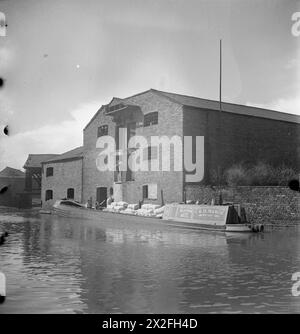 LES FEMMES DIRIGENT Un BATEAU : LA VIE À BORD DE LA BARGE DU CANAL 'HEATHER BELL', 1942 - Une cargaison de farine est déchargée de la 'HEATHER BELL' dans un entrepôt sur un canal, probablement le canal de Birmingham à Tipton Junction Banque D'Images