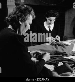 CRÉATEURS DE MODE LONDONIENS : LE TRAVAIL DES MEMBRES DE LA SOCIÉTÉ INCORPORÉE DES CRÉATEURS DE MODE LONDONIENS EN TEMPS DE GUERRE, LONDRES, ANGLETERRE, Royaume-Uni, 1944 - dans les salles de travail du créateur de mode Norman Hartnell à Londres, deux membres du personnel s'assoient à une table et se collent ensemble une blouse de l'après-midi Banque D'Images