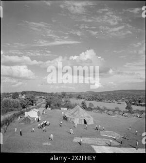 LES JEUNES BÉNÉVOLES AIDENT LES AGRICULTEURS BRITANNIQUES : CAMP AGRICOLE À Nunney CATCH, SOMERSET, ANGLETERRE, Royaume-Uni, 1943 - les garçons jouent au baseball au soleil dans le champ où ils campent au camp d'été des jeunes bénévoles à Nunney Catch, Somerset. Les nuages moelleux suspendus au-dessus du paysage du Somerset dominent la photographie Banque D'Images