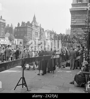 CÉLÉBRATIONS DE LA JOURNÉE VJ, 15 AOÛT 1945 - des foules attendent des nouvelles à la jonction de Whitehall avec Downing Street, 15 août 1945. La foule se compose de militaires et de civils, tous attendant la confirmation du premier ministre que la guerre au Japon est terminée. Clairement visibles en arrière-plan, ainsi qu'un bus londonien, sont le cénotaphe, le sommet de la Tour Victoria (qui fait partie des chambres du Parlement) et Big Ben Banque D'Images