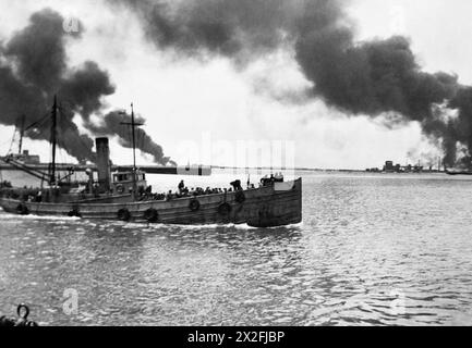 DUNKERQUE ET LA RETRAITE DE FRANCE 1940 - alors que les réservoirs de stockage de pétrole brûlent au loin, un chalutier bondé de têtes de troupes de Dunkerque de retour en Angleterre, juin 1940 Banque D'Images