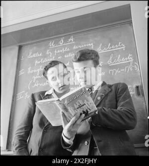 LES JEUNES BRITANNIQUES ÉTUDIENT L'HISTOIRE AMÉRICAINE : L'ÉDUCATION EN TEMPS DE GUERRE EN ANGLETERRE, 1943 - Ronald Wale (à gauche) et Ronald Prior se tiennent devant le tableau et lisent une copie du livre 'histoire du peuple américain' de C F Strong, lors d'une leçon sur l'Amérique à l'Albany Senior School Banque D'Images