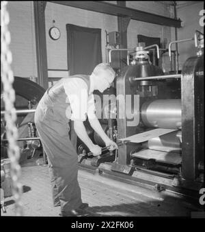 En 1944, au National Physical Laboratory de Teddington, un scientifique du département de métallurgie teste les effets du laminage à chaud et à froid sur une tôle en alliage métallique, démontrant la recherche métallurgique en temps de guerre. Banque D'Images