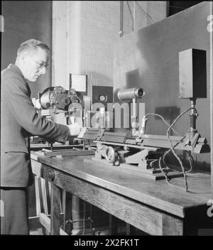 En 1944, au National Physical Laboratory de Teddington, Middlesex, en Angleterre, un scientifique de la section optique de la Division de la lumière mesure les plages de focalisation et les échelles de jumelles et de télescopes à l'aide d'appareils spécialisés pendant la recherche en temps de guerre. Banque D'Images