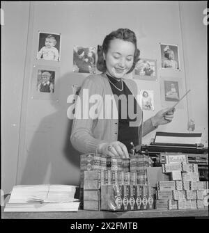 YMCA SNAPSHOTS FROM HOME : CIVILIAN PHOTOGRAPHERS AT WORK, UK, 1944 - Betty Brooks, secrétaire du programme « snapshots from Home » du YMCA organise des fournitures de films dans son bureau. Elle est responsable de la « distribution des demandes de clichés des soldats aux snapshots répertoriés dans toute la Grande-Bretagne ». Derrière elle sur le mur sont épinglés plusieurs exemples du travail des photographes amateurs Banque D'Images