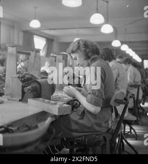 DES FAUTEUILS AUX BOMBARDIERS : TRAVAIL DE GUERRE AU SHOWROOM DE MEUBLES PERRINGS, KINGSTON, SURREY, 1943 - des travailleuses de guerre à temps partiel enroulent des bobines au showroom de meubles Perrings, qui a été partiellement converti en usine produisant du matériel électrique pour les bombardiers de la Royal Air Force Banque D'Images