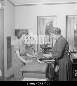 LES GÎTES DE FREEFOLK : LA VIE DANS LE VILLAGE DE FREEFOLK, HAMPSHIRE, ANGLETERRE, Royaume-Uni, 1943 - Mme Arrowsmith (à gauche) achète un paquet de cigarettes et quelques timbres à Freefolk Postmistress, 65 ans Mme Collis. Mme Collis a vécu sur le domaine toute sa vie, et la poste est dirigée par sa famille depuis 71 ans Banque D'Images