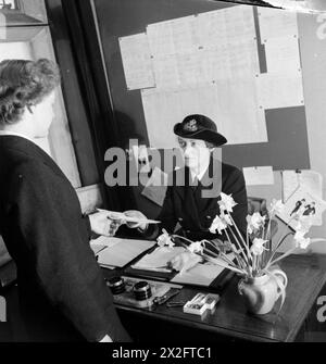 LA JEUNE FILLE INCONNUE DERRIÈRE LA BATAILLE MARITIME : LE TRAVAIL DU SERVICE NAVAL ROYAL FÉMININ, 1942 - maintenant entièrement enrôlée après deux semaines de formation, Wren Unknown recueille son mandat de voyage et ses ordres de l'officier en charge du dépôt. Ces documents lui indiquent à quelle base elle sera envoyée Banque D'Images