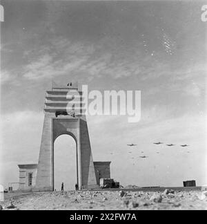 Des avions Curtiss Kittyhawk de la 239e Escadre de la RAF volent sur le terrain d'atterrissage de Marble Arch, en Libye, en passant devant le monument Arco dei Fileni sur la via Balbia, la route côtière entre la Tripolitaine et la Cyrénaïque, en 1939-1943. La photographie documente les opérations de la RAF en Afrique du Nord et au moyen-Orient. Banque D'Images