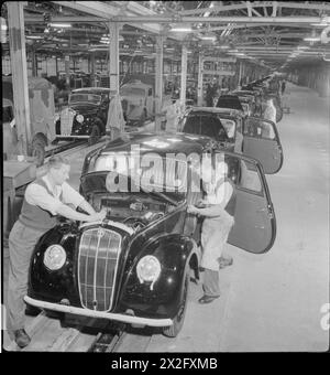 Les ouvriers assemblent et terminent des voitures sur une chaîne de production dans une usine automobile britannique en 1945, avec des véhicules qui s'étendent au loin. Banque D'Images