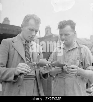 CAMP DE LONDRES DE L'ÉQUIPE DE RÉPARATION BLITZ : LA VIE QUOTIDIENNE AVEC LES ÉQUIPES DE RÉPARATION BLITZ, LONDRES, ANGLETERRE, Royaume-Uni, 1944 - le général Foreman J Wigley (de Darlington) et le Foreman H Uttley examinent un morceau des restes d'une bombe volante V1. Ils font partie d'une équipe de constructeurs qui sont venus à Londres de diverses régions du pays pour réparer les dégâts causés par ces bombes Banque D'Images