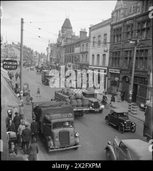 UNE IMAGE D'Une VILLE DU SUD : LIFE IN WARTIME READING, BERKSHIRE, ANGLETERRE, Royaume-Uni, 1945 - Une vue générale de la rue Broad Street animée à Reading, montrant des véhicules et des piétons vaquant à leurs affaires quotidiennes. Une cycliste est visible à droite de la photo. Selon la légende originale 'au premier plan, les barils de bière passant des barils de lait représentent deux des principales industries de Reading. Sur la gauche, une voiture de production du Ministère de l'aviation stationnée représente l'un des ministères nationaux avec un bureau local. Il y a un timbre du ministère des Transports de guerre sur le camion au premier plan gauche. Po Banque D'Images