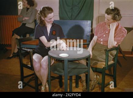 LE BALLET RAMBERT VISITANT UNE USINE D'AVIONS EN GRANDE-BRETAGNE - danseurs du Ballet Rambert, sous les auspices du CEMA (Conseil pour l'encouragement de la musique et des Arts), visitant une usine d'avions dans les Midlands. Photos : dans l'auberge de l'usine, où le corps de ballet est resté pour la nuit, Sally Gilmour (à gauche), ballerine, discute des emplois avec Winifred Simpson, agent de bien-être de l'auberge Banque D'Images