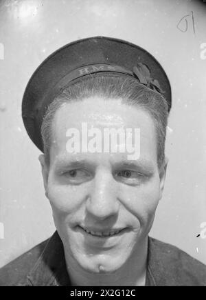 À bord du cuirassé HMS Rodney en septembre 1940, officiers et hommes se tiennent sur le pont ; un stoker, avec 13 ans de service et trois badges de combat, fait partie de l’équipage de catapulte du navire. Banque D'Images