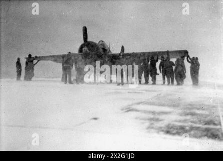 CONVOI BRITANNIQUE EN RUSSIE. LE 1945, À BORD DU PORTE-AVIONS D'ESCORTE BRITANNIQUE HMS CAMPANIA LORS D'UN CONVOI À DESTINATION DE LA RUSSIE LORSQUE LE TEMPS ARCTIQUE ÉTAIT AMER. - Un Wildcat en train d'être rangé sur le pont d'envol de CAMPANIE dans des conditions arctiques Banque D'Images