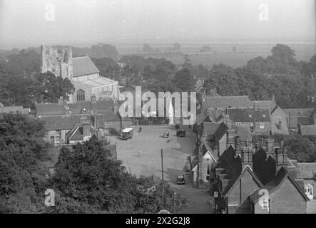 VILLAGE D'INVASION : LA VIE QUOTIDIENNE À ORFORD, SUFFOLK, ANGLETERRE, 1941 - Une vue large du village d'Orford, prise du haut de la tour du château, montrant maisons et véhicules. Dominant l'horizon est la tour du parfait Église de Barthélemy, visible à gauche de la photo, juste en face des champs et des arbres en arrière-plan Banque D'Images