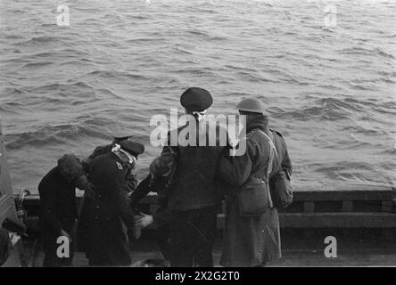 OPÉRATIONS LOFOTEN. DÉCEMBRE 1941, À BORD D'UN DES NAVIRES DE GUERRE HM PARTICIPANT À DES OPÉRATIONS DANS LES ÎLES LOFOTEN, NORVÈGE. LES QUISLINGS NORVÉGIENS ET LES ALLEMANDS SONT FAITS PRISONNIERS PENDANT LES OPÉRATIONS. - Prisonniers allemands emmenés à terre dans un drifter. Ils ont tous été soigneusement pliés à l'aveugle Banque D'Images