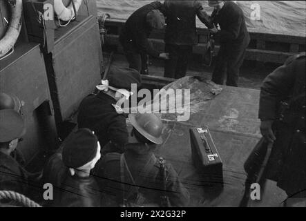 OPÉRATIONS LOFOTEN. DÉCEMBRE 1941, À BORD D'UN DES NAVIRES DE GUERRE HM PARTICIPANT À DES OPÉRATIONS DANS LES ÎLES LOFOTEN, NORVÈGE. LES QUISLINGS NORVÉGIENS ET LES ALLEMANDS SONT FAITS PRISONNIERS PENDANT LES OPÉRATIONS. - Prisonniers allemands emmenés à terre dans un drifter. Ils ont tous été soigneusement pliés à l'aveugle Banque D'Images