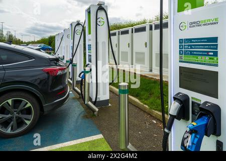Voitures à la station de recharge de véhicules électriques, qui fait partie du réseau de points de recharge Gridserve appelé Gridserve Electric Highway, Angleterre Royaume-Uni Banque D'Images