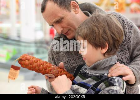 petit garçon et son grand-père choisissent la saucisse dans la boutique ; ensemble Banque D'Images