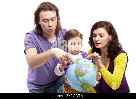 Père et mère montrent quelque chose sur la boule gonflable-terre à la petite fille, qui le tient dans ses bras. Banque D'Images