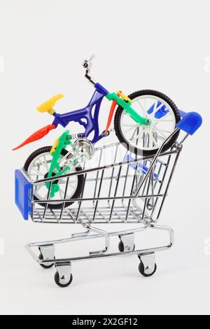 bicyclette à deux roues jouet en plastique coloré dans le panier d'achat sur fond blanc Banque D'Images