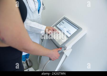 Un praticien de la santé assiste une femme avec un test de composition corporelle à l'aide d'un équipement de pointe. Banque D'Images