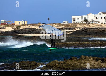 Planche de surf à l'aide d'une planche de surf avec lame d'hydrofoil sous-marine, négociant la côte rocheuse dans la mer agitée. El Cotillo, Fuerteventura. Fév 2024 Banque D'Images