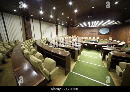 Auditorium table ronde en chêne et fauteuils beiges autour et rangées de bureaux et fauteuils. Banque D'Images