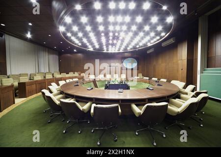 Auditorium avec table ronde en chêne, fauteuils beiges autour et fleurs et affichages au centre. Banque D'Images