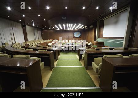 Auditorium avec table ronde en chêne et fauteuils beiges autour. Banque D'Images