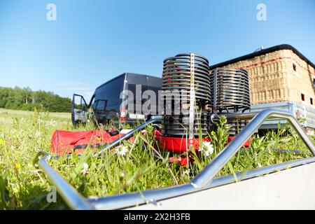 Construction métallique avec brûleurs à gaz pour montgolfières se tient sur le sol dans l'herbe près du panier tissé. Banque D'Images