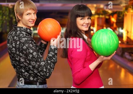 femme heureuse et mari avec des balles dans le club de bowling se tiennent sur le côté de la caméra Banque D'Images