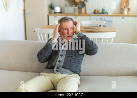 Maux de tête. Malheureux homme âgé d'âge moyen souffrant de maux de tête malade frottant les tempes à la maison. Vieux grand-père aîné mature touchant les temples éprouvant du stress. Homme sentant mal à la tête Banque D'Images