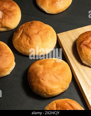 Petit pain rond cuit frais isolé, petits pains ronds sur un fond de baume et de bois. Banque D'Images