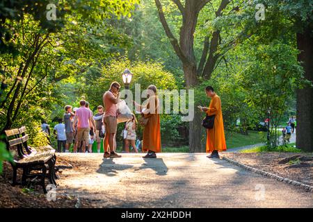 Des moines vêtus de robes oranges traditionnelles s'entretiennent avec les visiteurs à Central Park, New York City Banque D'Images