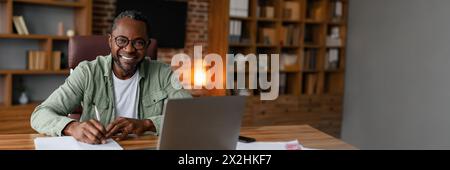 Un afro-américain d'âge moyen travaille sur ordinateur portable à la maison Banque D'Images
