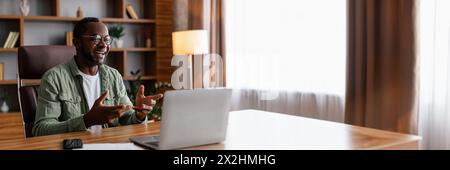 Rire homme afro-américain mature travaille sur ordinateur portable à table Banque D'Images