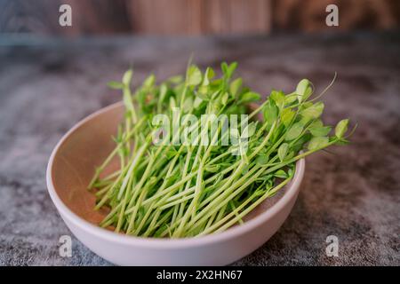 Bouquet de microgreens de pois juteux se trouve dans une assiette sur une table en marbre Banque D'Images